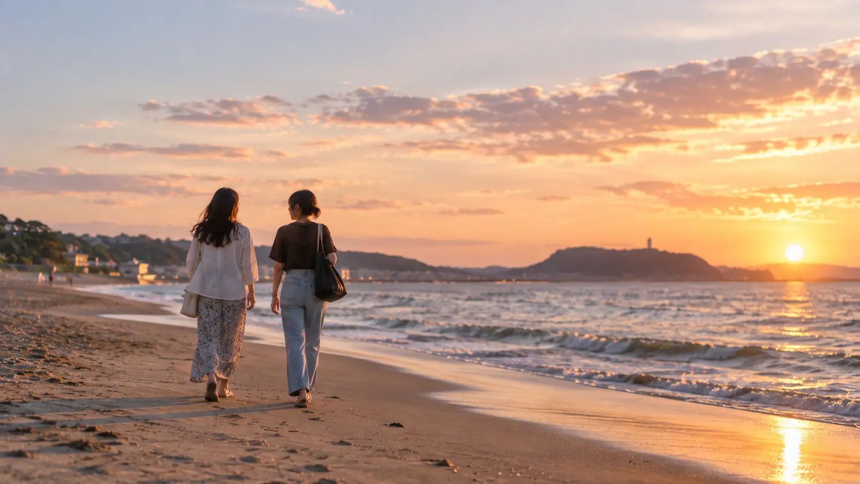 夕暮れの海辺を並んで歩く二人の女性